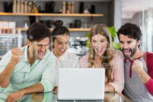 Group of excited friends using laptop