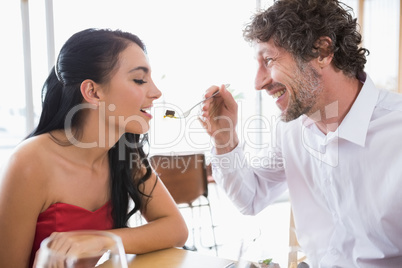 Man feeding food to woman