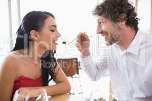 Man feeding food to woman