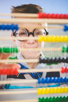 Close-up of schoolkid looking through abacus in classroom