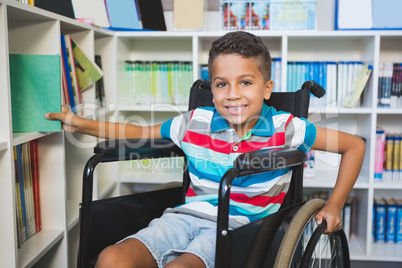 Disabled boy selecting a book from bookshelf in library