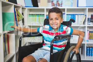 Disabled boy selecting a book from bookshelf in library