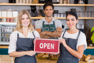 Smiling colleagues showing signboard with open sign