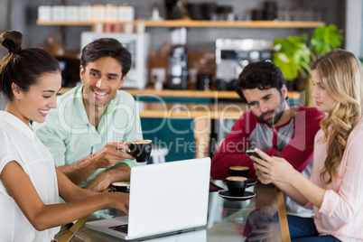 Group of friends using mobile phone and laptop