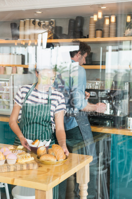 Waitress arranging dessert and snack on the counter while waiter