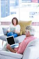 Mature man using notebook while sitting by woman