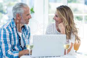 Mature couple talking while sitting by table