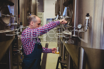 Manufacturer pouring beer in glass at brewery