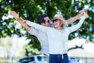 Couple with arms outstretched against trees