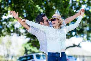 Couple with arms outstretched against trees