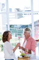 Mature man giving flower to woman