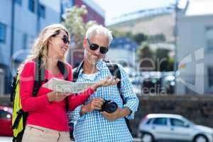 Mature couple holding map and camera in city