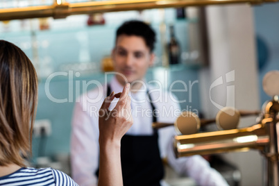 Woman gesturing while talking with bartender