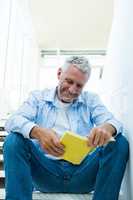 Smiling man reading book on steps