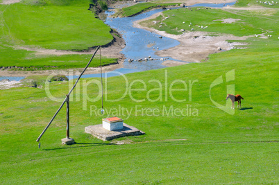 Green meadow, river and well Crane