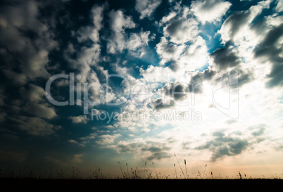 Horizontal ground silhouette with dramatic clouds and sunshine b