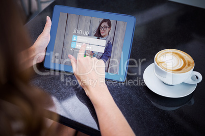 Composite image of woman having coffee and using her tablet