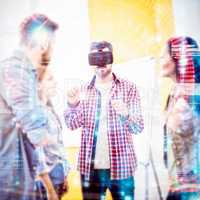 Coworkers looking at businessman wearing virtual reality headset