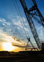 Vertical vivid sand mining machine silhouette yellow burning sun