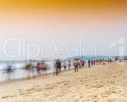 Horizontal vivid vibrant sunset on Indian beach with crowd of pe