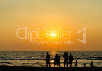 Big family silhouette meeting vivid orange sunset ocean horizon