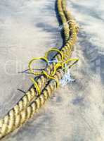 Vertical vivid yellow rope on the sand beach background backdrop