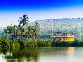 Horizontal vivid Indian house palms with river reflection backgr
