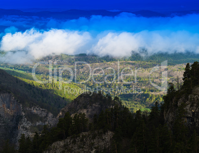 Horizontal vivid cloudscape in mountain forest background