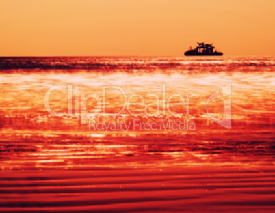 Horizontal vivid orange ship silhouette in ocean blurred backgro