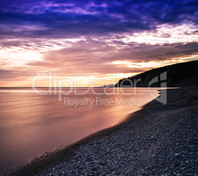 Horizontal dramatic sunset on stony beach background backdrop