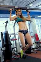At gym. Image of pretty woman tightening on bar