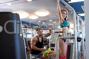 At gym. Coach controls girl training on simulator