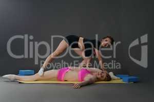 Smiling brunette helps her friend to stretch