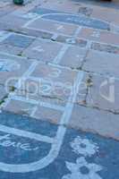 Hopscotch on an asphalt floor with chalk drawings of numbers and