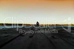 Lone man on pier orange sunset