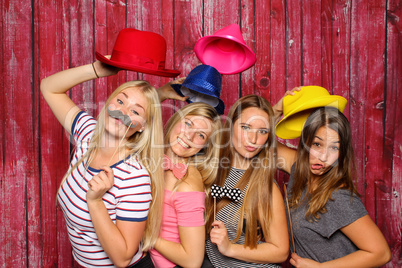 Junge Frauen haben Spaß mit einer Fotobox - Mädchen mit Hüten und Bärte