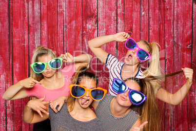 Mädchengruppe mit Brillen albern vor einer Fotobox  herum