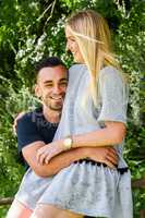 Smiling blonde sitting on gate with boyfriend