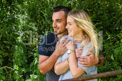 Smiling man holding blonde girlfriend behind gate