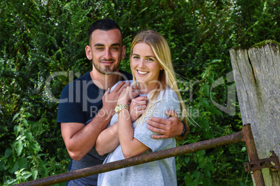 Man hugging blonde girlfriend by iron gate