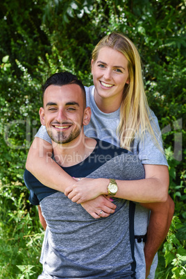 Smiling blonde woman holding boyfriend from behind