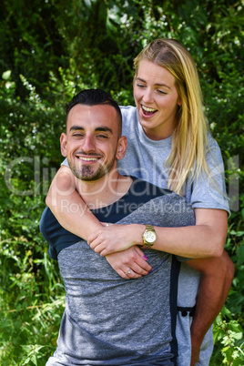Laughing blonde woman holding boyfriend from behind