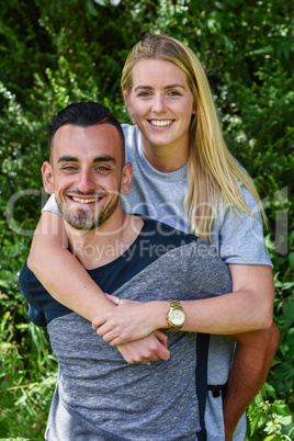 Smiling blonde woman cuddling boyfriend from behind