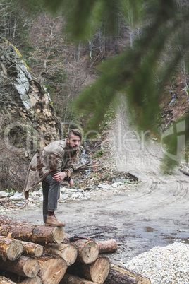 Young men on logs in the forest. Pine trees