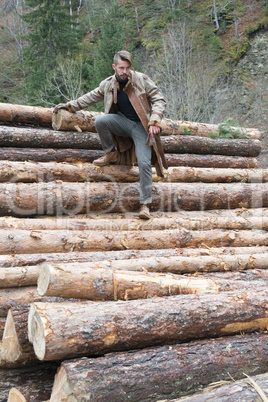 Young men on logs in the forest. Pine trees