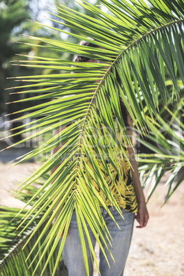 Woman hidden behind palm