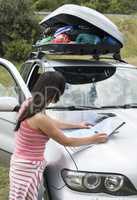 Woman looking at map on the car hood