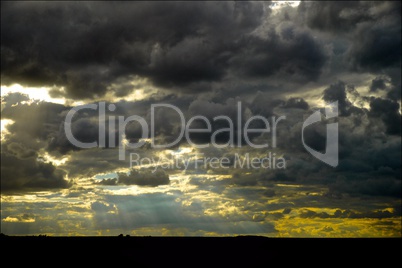 storm dark clouds over field with sun rays