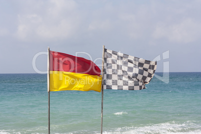 black and white checkered flag and surf lifesaving flag on beach photo