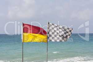 black and white checkered flag and surf lifesaving flag on beach photo